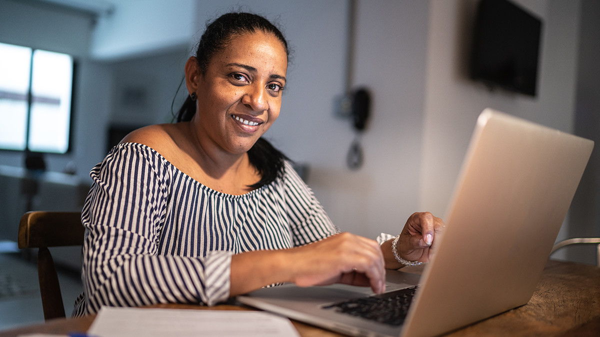 Smiling woman working on a laptop at a table at home
