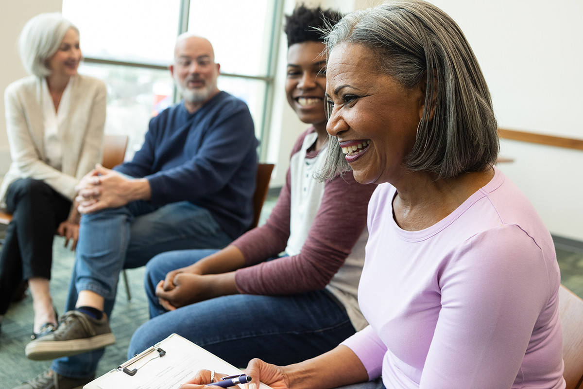 Group of adults sitting in a circle and smiling during a community workshop
