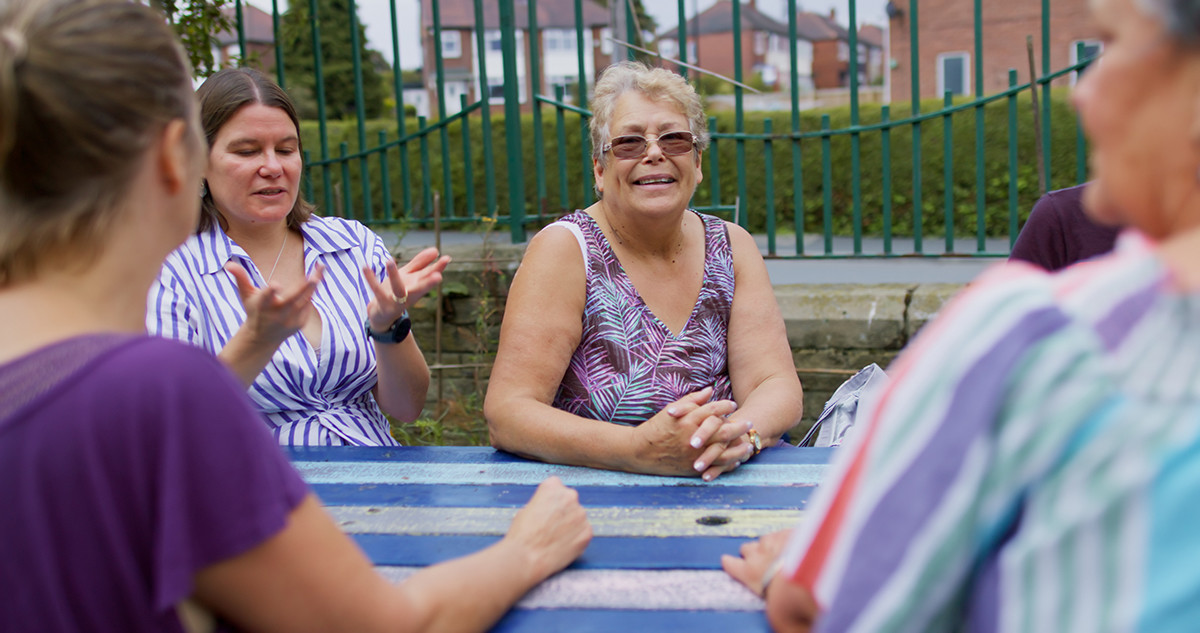 Group of women talking and laughing around an outdoor table